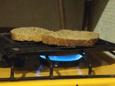 Pan tostándose sobre la llama azul del biogás en la cocina de la casa piloto