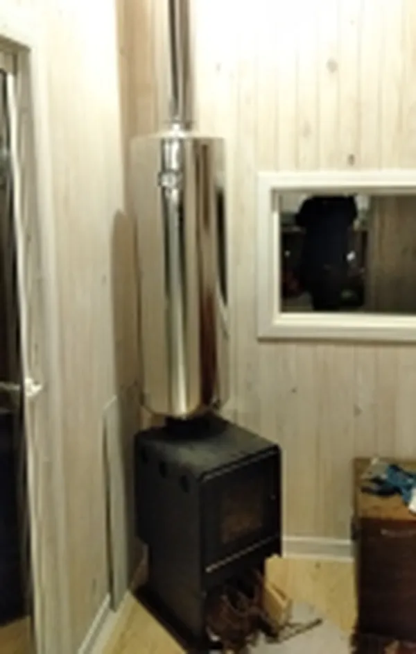Estufa de combustión lenta con termocañón de acero inoxidable dentro de la casa piloto